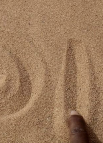 A finger draws letters in the sand (photo)